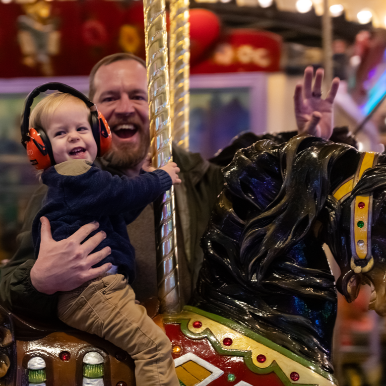 child and father on carousel