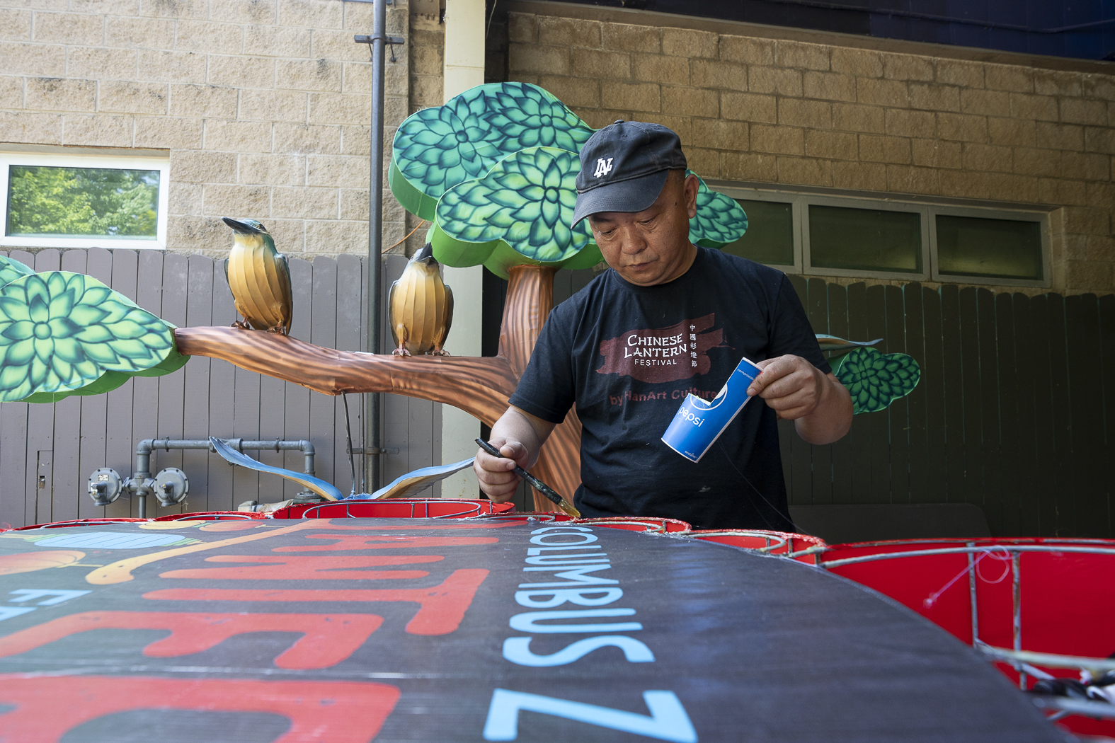 man painting lantern sign