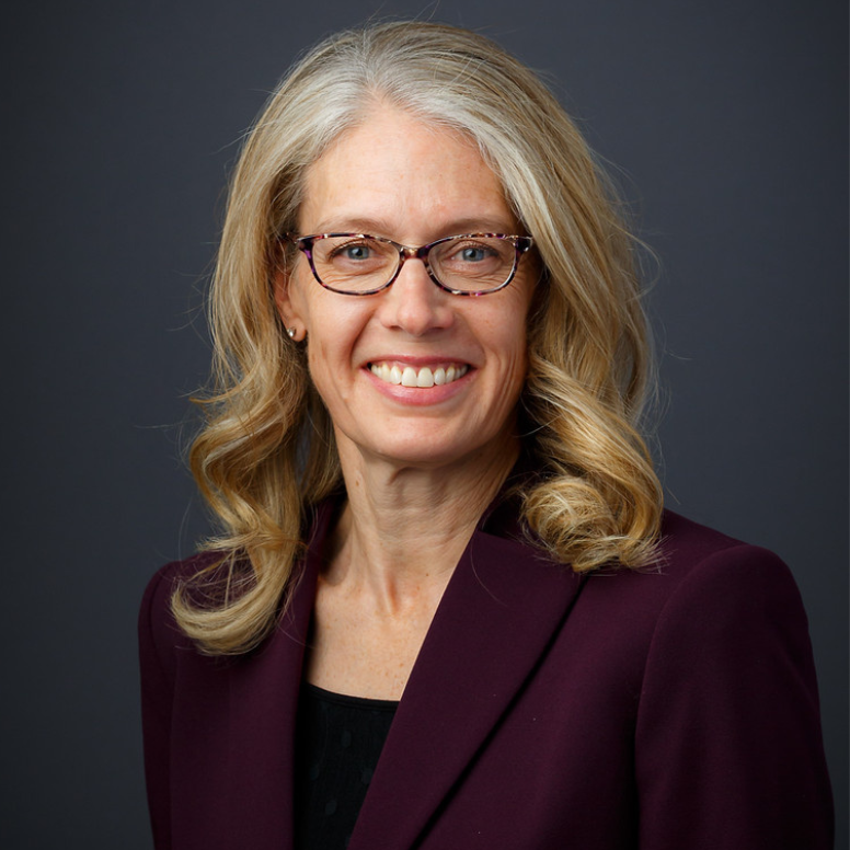 Jessica Mayer wearing plum-colored suit jacket and smiling at camera