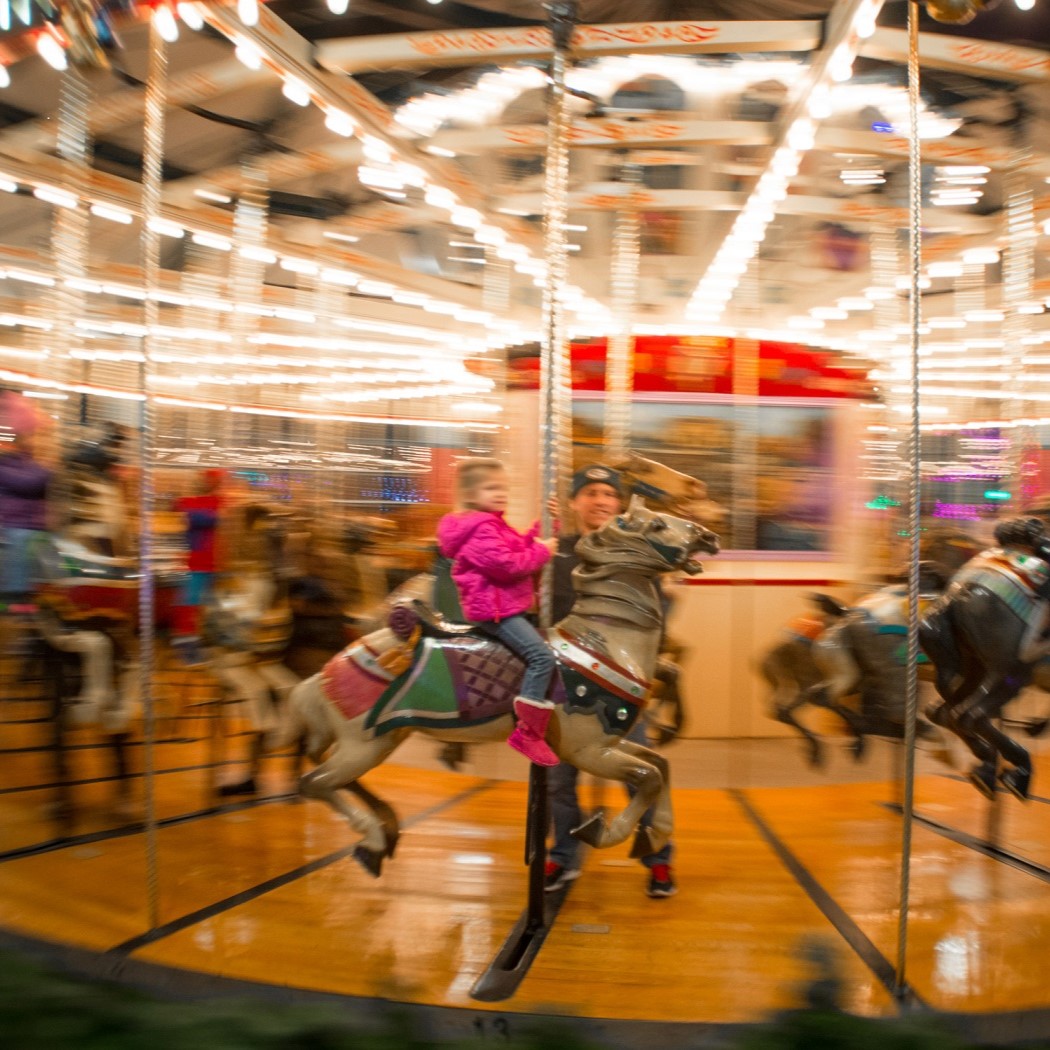 child on carousel with father figure