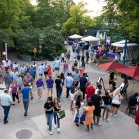 Guests walk down pathway and stop at tents to sample food and beverages during Zoofari