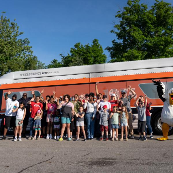 group of people smiling and posing in front of orange bus